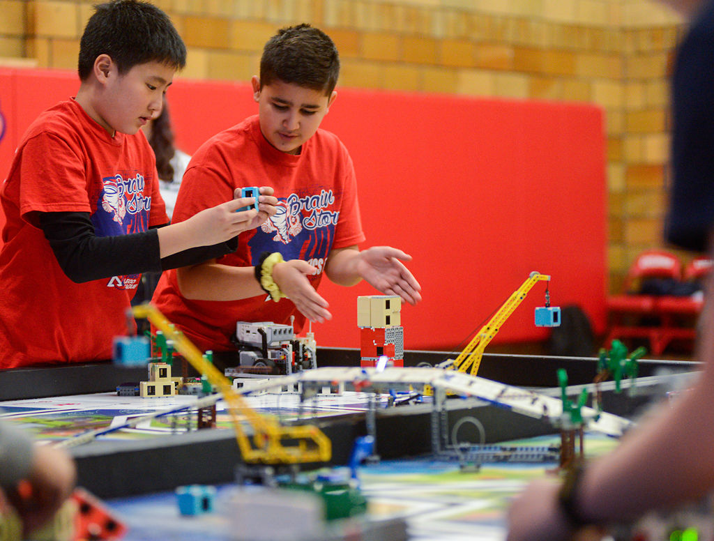 From left, Liang Lim, 11, and Aramis Guzman, 12, make changes to their LEGO robot